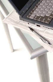 Black laptop computer and pen on top of newspapers